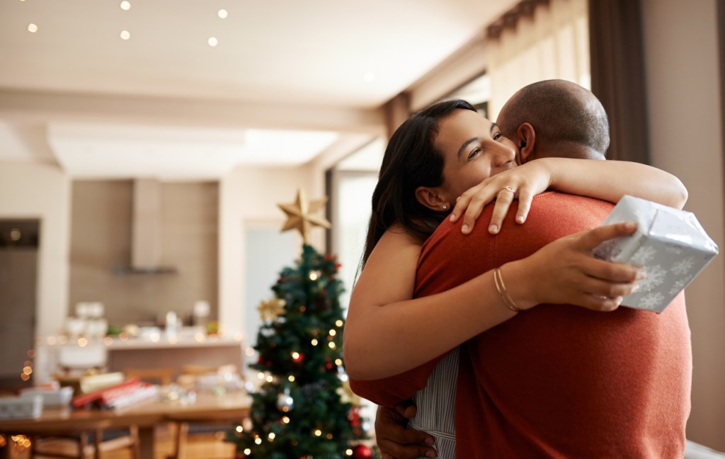 Shot of a happy young couple exchanging Christmas gifts at home